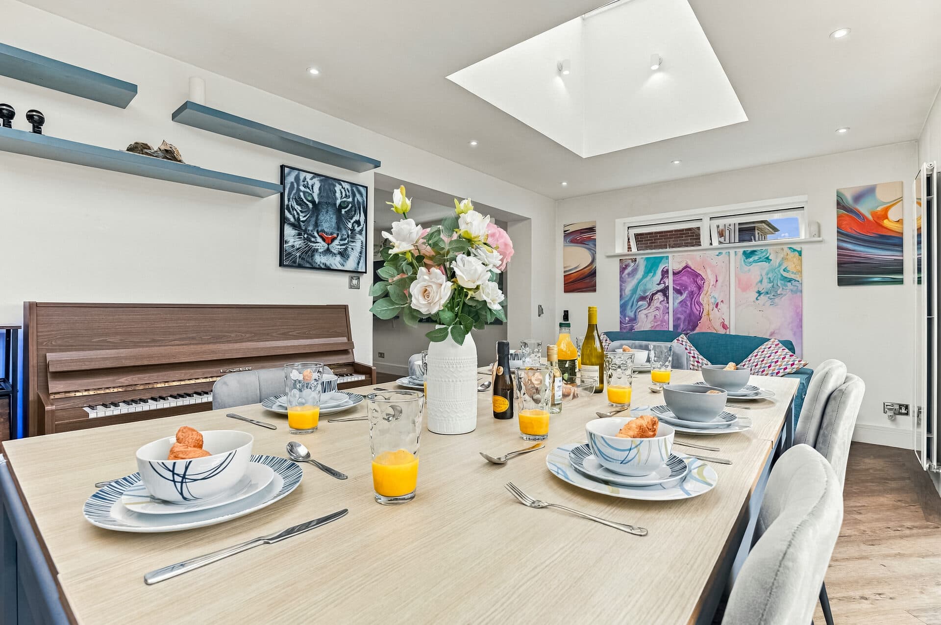 Dining table set for a group, with a piano and garden view